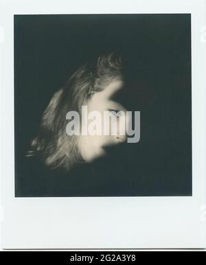 Instant shot of black and white crop face of young lady looking at camera in obscurity in Lapland Stock Photo