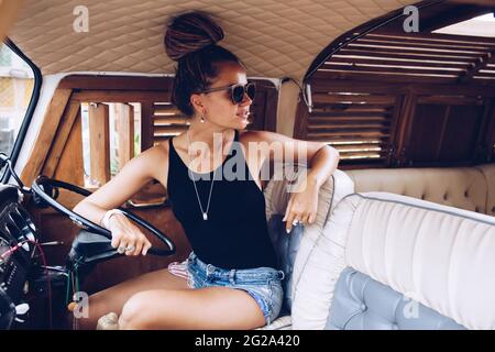 Smiling Woman sitting in vintage van on street Stock Photo