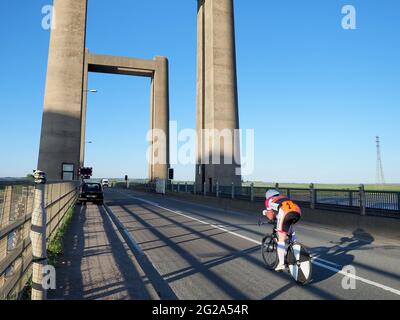 Iwade, Kent, UK. 9th June 2021. Wigmore Cycling Club organised a 10 mile time trial on the new 'Q10/45' course, which runs from Iwade to the Cowstead roundabout on the Isle of Sheppey. Amateur riders pass through the iconic Kingsferry Bridge landmark four times, as they attempt to complete the 10 mile course in the quickest time possible after being set off at intervals. Pictured: riders passing over the Kingsferry Bridge. Credit: James Bell/Alamy Live News Stock Photo