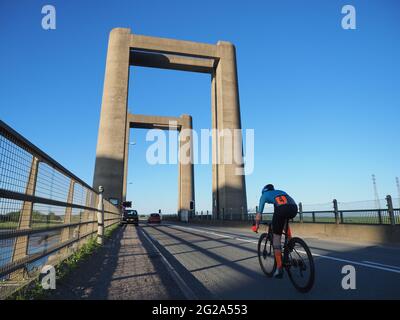 Iwade, Kent, UK. 9th June 2021. Wigmore Cycling Club organised a 10 mile time trial on the new 'Q10/45' course, which runs from Iwade to the Cowstead roundabout on the Isle of Sheppey. Amateur riders pass through the iconic Kingsferry Bridge landmark four times, as they attempt to complete the 10 mile course in the quickest time possible after being set off at intervals. Pictured: riders passing over the Kingsferry Bridge. Credit: James Bell/Alamy Live News Stock Photo