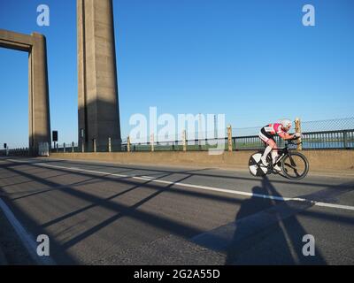 Iwade, Kent, UK. 9th June 2021. Wigmore Cycling Club organised a 10 mile time trial on the new 'Q10/45' course, which runs from Iwade to the Cowstead roundabout on the Isle of Sheppey. Amateur riders pass through the iconic Kingsferry Bridge landmark four times, as they attempt to complete the 10 mile course in the quickest time possible after being set off at intervals. Pictured: riders passing over the Kingsferry Bridge. Credit: James Bell/Alamy Live News Stock Photo