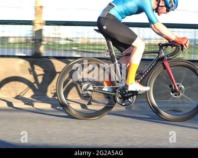 Iwade, Kent, UK. 9th June 2021. Wigmore Cycling Club organised a 10 mile time trial on the new 'Q10/45' course, which runs from Iwade to the Cowstead roundabout on the Isle of Sheppey. Amateur riders pass through the iconic Kingsferry Bridge landmark four times, as they attempt to complete the 10 mile course in the quickest time possible after being set off at intervals. Pictured: riders passing over the Kingsferry Bridge. Credit: James Bell/Alamy Live News Stock Photo