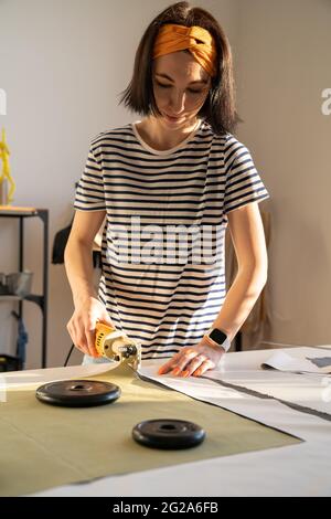 Cutting and sewing in tailor studio: sewer young woman work with fabric in design workshop studio Stock Photo