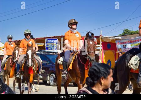 Pushkar, India - November 10, 2016: foreigner tourists riding horses with helmet in the biggest fair of Pushkar in the state of Rajasthan Stock Photo