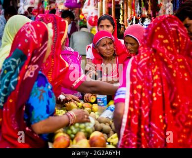 Pushkar, India - November 10, 2016: Few Indian women in colorful saree while covering their head buying fruits in group in the state of Rajasthan Stock Photo