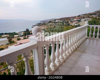 Traditional Greek architecture terrace balcony with white balusters. View on Aegean sea coast. Summer scenic view from country house near Athens, Gree Stock Photo