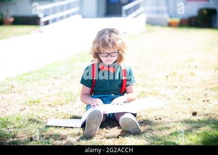 smart curious nerd in glasses reading book study with copybook outdoor, school education Stock Photo