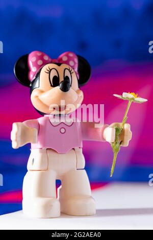 New York, USA - May 25, 2021: A close up shot of a miniature famous Disney character Minnie Mouse Disney character holding a flower. Stock Photo
