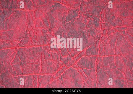 Dark red genuine leather with folds, artificially dyed. Background, pattern, texture. Stock Photo