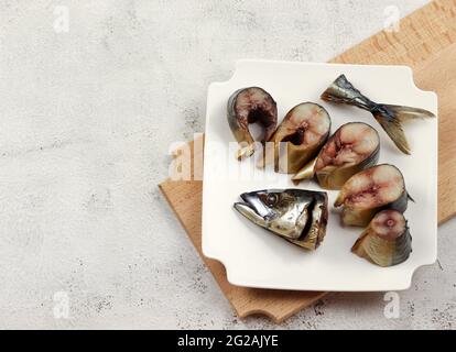 Slices of smoked fish mackerel on a white rectangular plate on a light gray background. Top view, flat lay Stock Photo