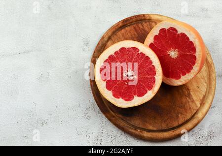 Sliced red grapefruit on a wooden cutting board on a light gray background. Top view, flat lay Stock Photo