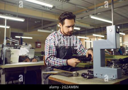 Worker using special tools and making new leather boots at workshop of shoe factory Stock Photo