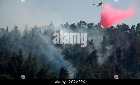 A firefighting aircraft drops flame retardant on a massive forest wildfire near the Maale Hahamisha kibbutz in the area of the Arab-Israeli village of Abu Ghosh on June 09, 2021 near Jerusalem, Israel. A major fire broke out in forested areas west of Jerusalem, prompting the Israel Fire and Rescue Services to evacuate residents in the area. Stock Photo