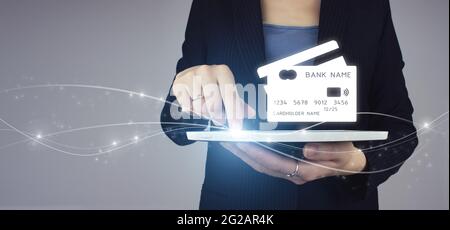 Mobile banking network, online payment, digital marketing. White tablet in businesswoman hand with digital hologram virtual credit card sign on grey b Stock Photo