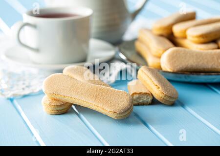 Italian cookie savoiardi. Sweet biscuits. Sponge cookies tiramisu on blue table. Stock Photo