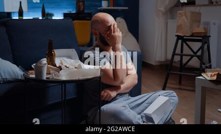 Helpless, frustrated, confused, desperate adult man sitting on floor reading with tears eviction notice in paperwork letter. Shocked, worried tenant by warning notification for unpaid bank bills Stock Photo