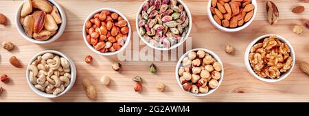 Nuts panorama. Pistachios, peanuts, walnuts and many other nuts, shot from the top on a rustic wooden background Stock Photo