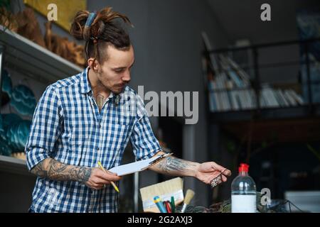 Bearded young man with clipboard working in workshop Stock Photo