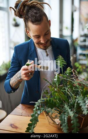 Cheerful young man cleaning plant leaves with brush Stock Photo