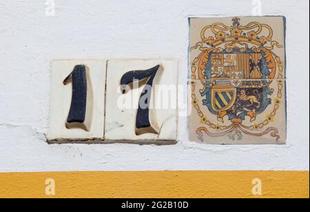 Seville, Spain - Sept 27th 2020: Royal Alcazars of Seville. Coat of arms glazed tiled and 17 door number of Patio de Banderas section Stock Photo