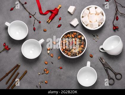 Top view of workplace with rose hips, organic peanuts, birdseeds, coconut fat and tools to create bird feeders in teacups. Stock Photo