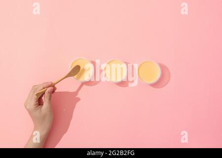 Hand putting creme caramel in minimalist style setup on pink background Stock Photo