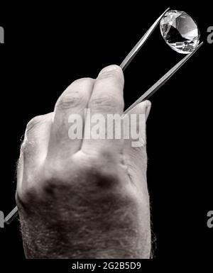 Large gemstone in jeweler's hand close up. Gem identifying and evaluating process. Stock Photo