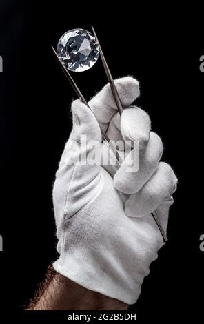 Large gemstone in jeweler's hand close up. Gem identifying and evaluating process. Stock Photo