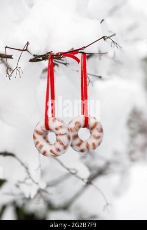 Two homemade peanut donut suet cakes hanging in the snowy garden. Feeding the birds in winter. Copy space. Stock Photo