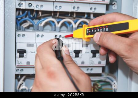 Electrician with multimeter probe at an electrical switchgear ca Stock Photo