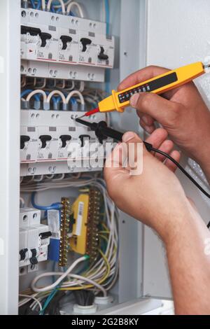 Electrician with multimeter probe at an electrical switchgear ca Stock Photo