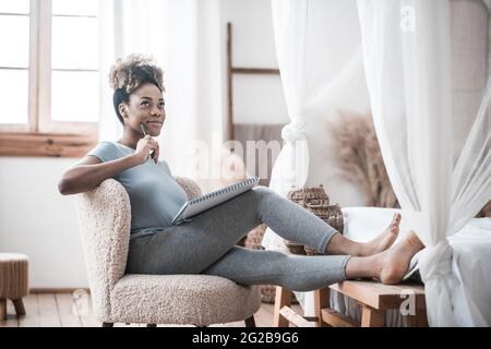 Pensive dark-skinned woman with notebook and pen Stock Photo