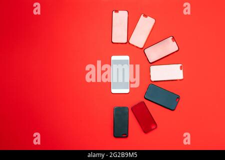 Choice of multicolored plastic back covers for mobile phones on red background with a smart phone on the side Stock Photo