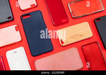 Pile of multicolored plastic back covers for mobile phone. Choice of smart phone protector accessories on red background. A lot of silicone phone back Stock Photo