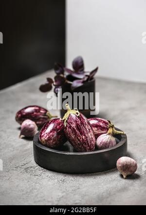 Fresh raw purple mini eggplants, garlic and basil. Stock Photo