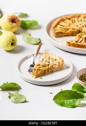 Piece of tasty homemade apple tart with green pistachios ready to eat. Stock Photo