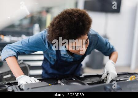 young african american mechanic fixing car motor in garage Stock Photo