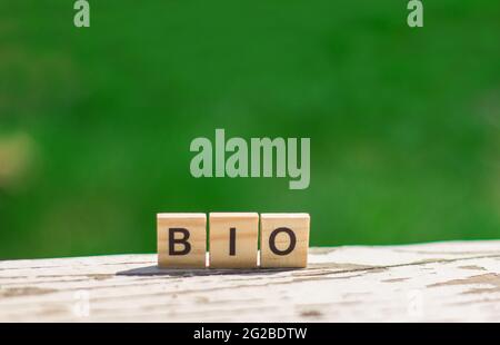 Word BIO message sign of wooden cubes on a light table against a background of green leaves in soft focus Stock Photo