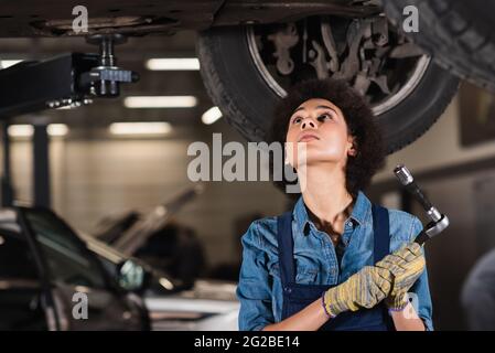 young african american mechanic repairing bottom of car in garage Stock Photo