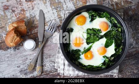 Eggs with spinach in a frying pan. Healthy breakfast. The keto diet. Stock Photo