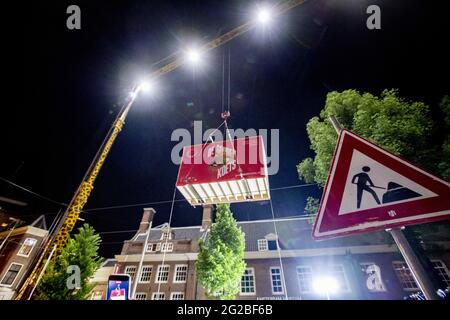 At night, a wooden box containing the restored Golden Coach is hoisted over the roof of the Amsterdam Museum. The Golden Coach, which weighs more than 2,800 kilograms, will be on display to the public as the centerpiece of the well-named exhibition exploring years of controversy surrounding this gift from the city of Amsterdam to the Netherlands' royal family from June 18 to February 27, 2022. The arrival of the Golden Coach in the Amsterdam Museum is the official moment that the restored Golden Coach returns to the city that gave it to Wilhelmina in 1898: Amsterdam. Amsterdam, Netherlands on Stock Photo