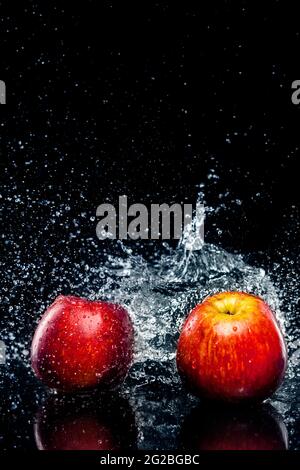 Two apples with splash of water isolated on black background. Stock Photo