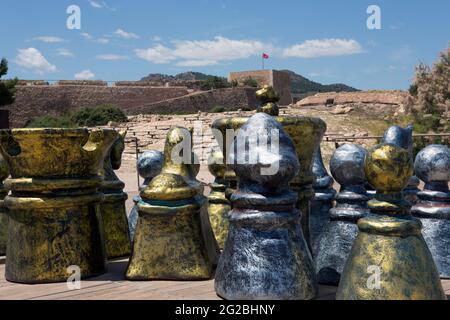 Giant chess with pieces in gold and silver color, put together facing the wall and tower of the castle of the medieval castle in Lorca. Stock Photo