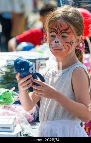 Scenes from Little Portugal festival. Little girl with her face painted like a tiger, holding a soft toy.   Little Portugal festival is a bustling ann Stock Photo