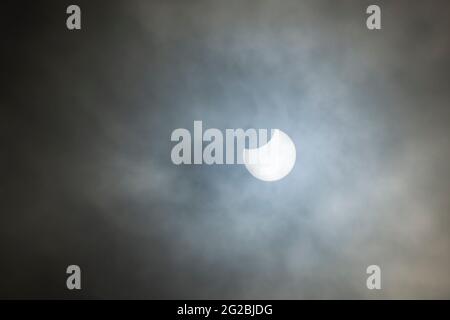 A partial solar eclipse of the Sun seen through cloud on 10th June 2021 viewed from North Somerset, England. Stock Photo