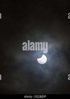 A partial solar eclipse of the Sun seen through cloud on 10th June 2021 viewed from North Somerset, England. Stock Photo