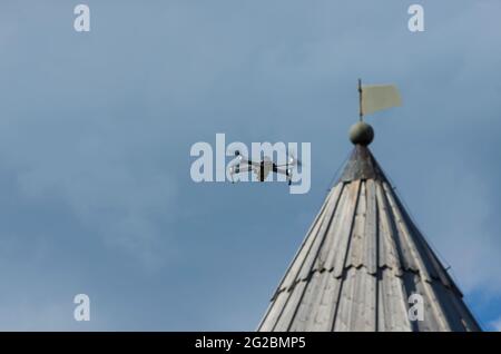 Quadrocopter drone in flight on the background the roof of an old tower and space for text on the left (Staraya Ladoga, St. Petersburg, Russia) Stock Photo