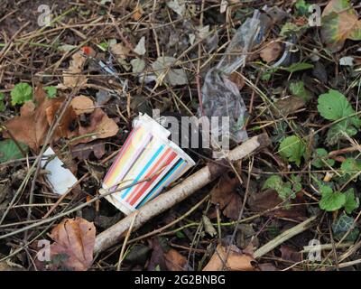 A rainbow-coloured paper cup and plastic trash lying on the ground roadside in Heidelberg, Germany. Stock Photo