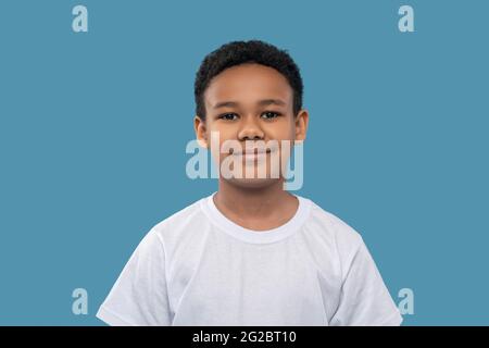 Smiling friendly dark-skinned boy on light blue background Stock Photo
