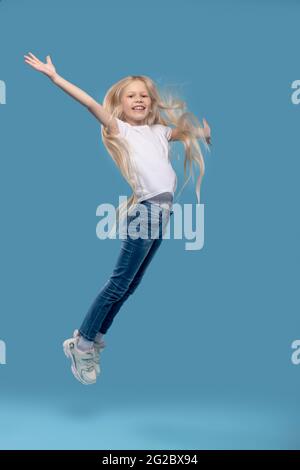 Girl jumping upwards with her hands to sides Stock Photo